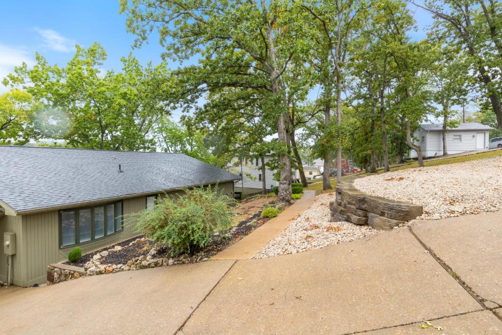 ein grünes Haus mit einer Einfahrt und Bäumen in der Unterkunft Game Room, Dock Life, Fire Pit & Hot Tub! in Four Seasons