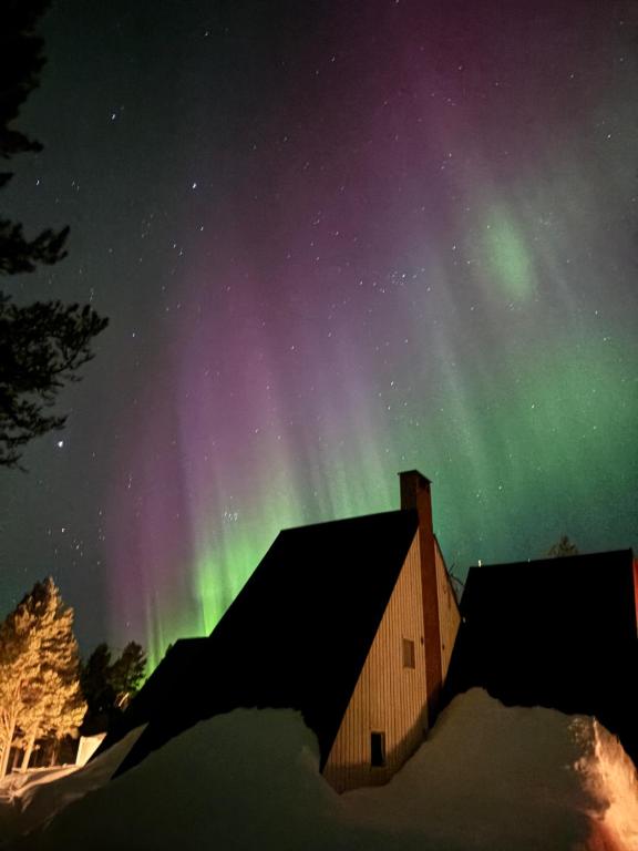 an aurora over a building in the snow at Arctic Lodge Hetan Kota in Enontekiö