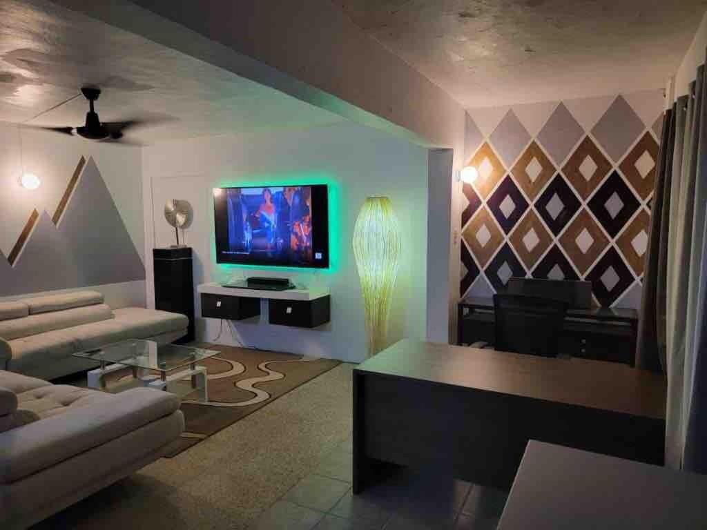Una sala de estar con un sofá y un televisor. en La marquesina guess home, en Loiza