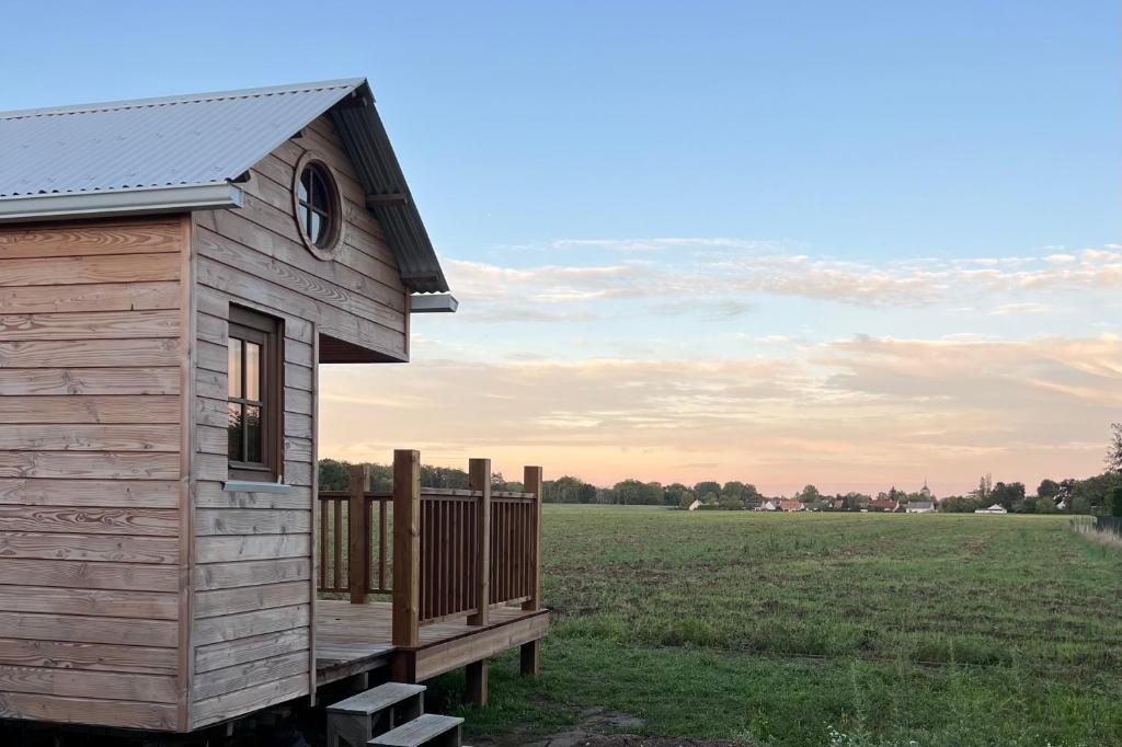 a tiny house with a deck in a field at Tiny House chez Annette in Darvoy