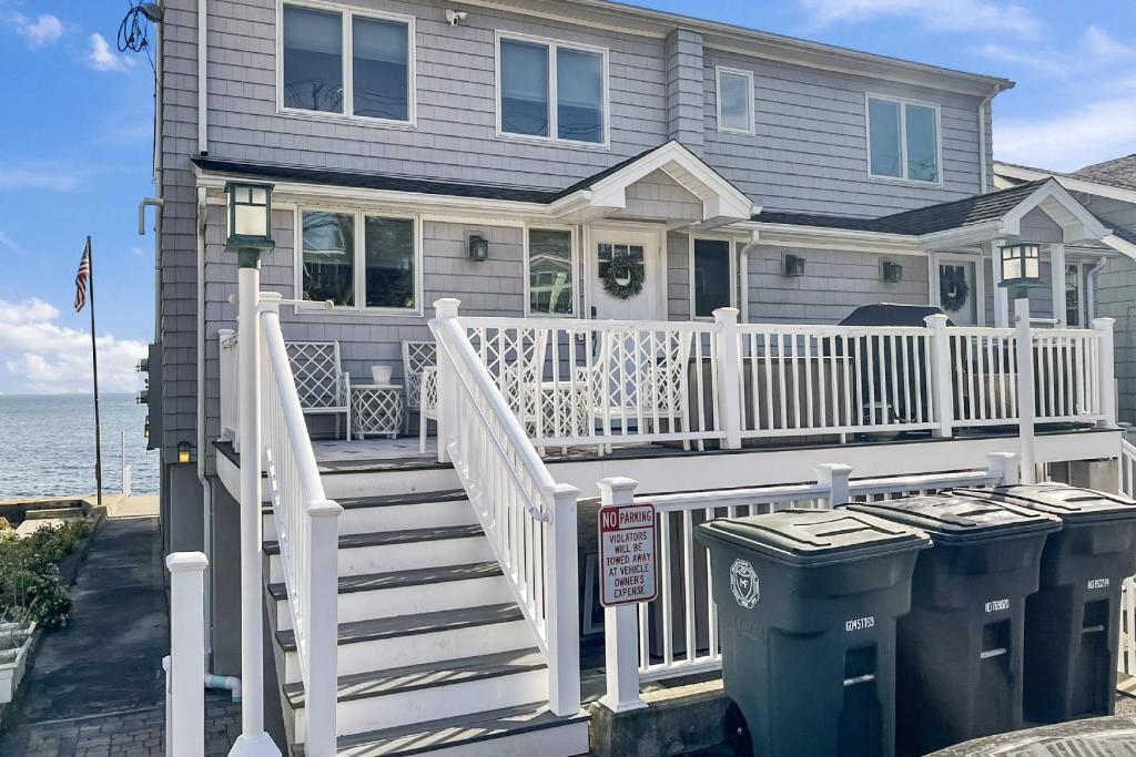 een huis met een witte leuning en een trap naast de oceaan bij Sunrise to Sunset Waterfront Retreat in Milford