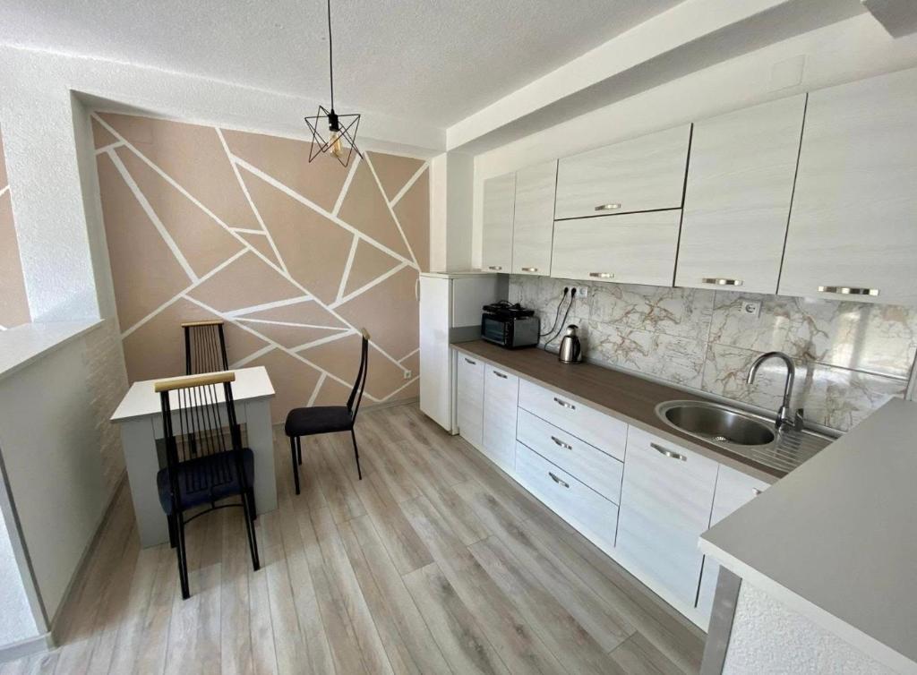 una cucina con armadi bianchi, tavolo e lavandino di Villa Lilak a Bihać