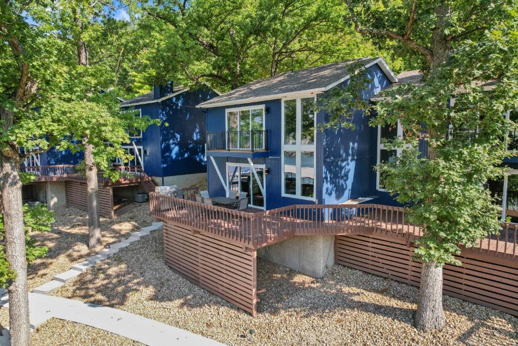 a blue house with a deck and trees at Walk to The Strip! Great Cove Water for Lake Fun in Lake Ozark