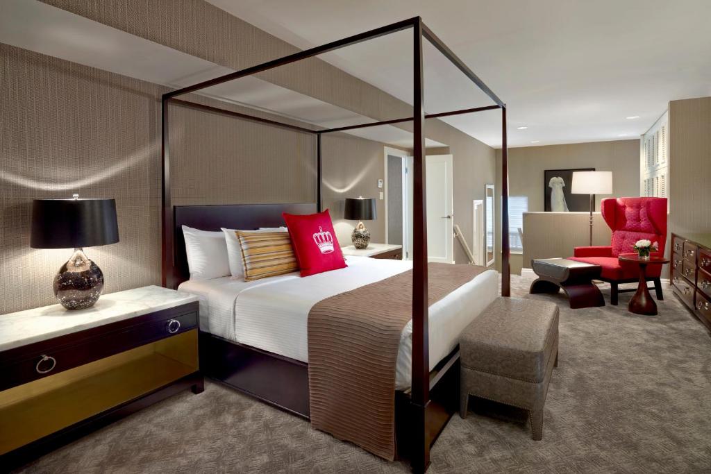 a bedroom with a canopy bed and a red chair at The Omni King Edward Hotel in Toronto