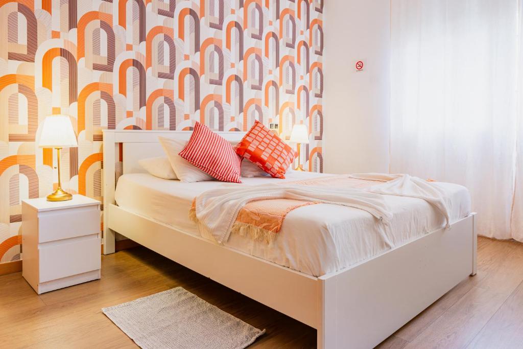 un dormitorio con una cama blanca con almohadas naranjas y blancas en Quartos da Expo, en Lisboa