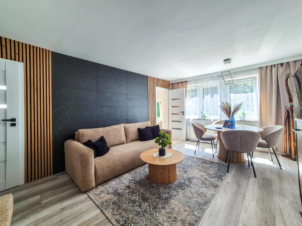 a living room with a couch and a table at Przystanek Karpacz - Apartament Rejkiawik in Karpacz
