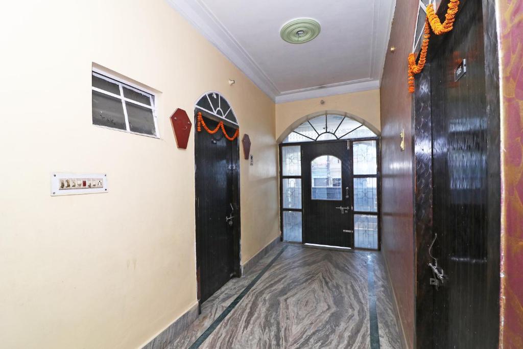 un couloir avec une porte noire et une fenêtre dans l'établissement Hotel O Sonora Hotel, à Dhanbād