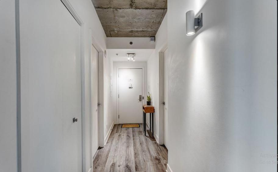 un couloir avec des murs blancs et du parquet et une porte blanche dans l'établissement Corporate Stays Le Shaughn 2 Bedroom, à Montréal