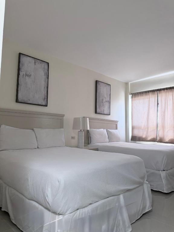two white beds in a bedroom with two windows at Hotel La Mansión in Río Bravo
