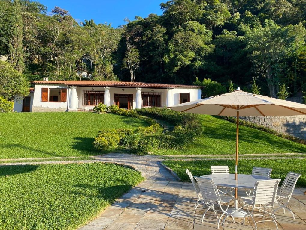 a table and chairs with an umbrella in front of a house at Casa Vale da Serra - Petrópolis in Petrópolis