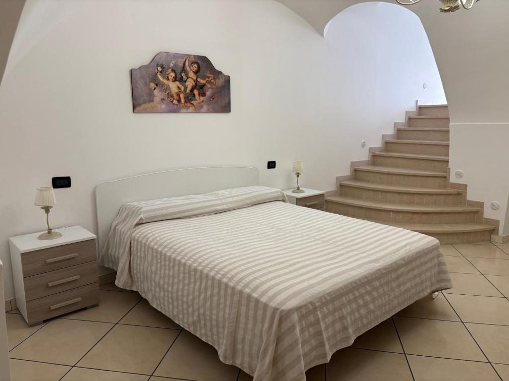 a white bedroom with a bed and a staircase at Amber house in Lesina