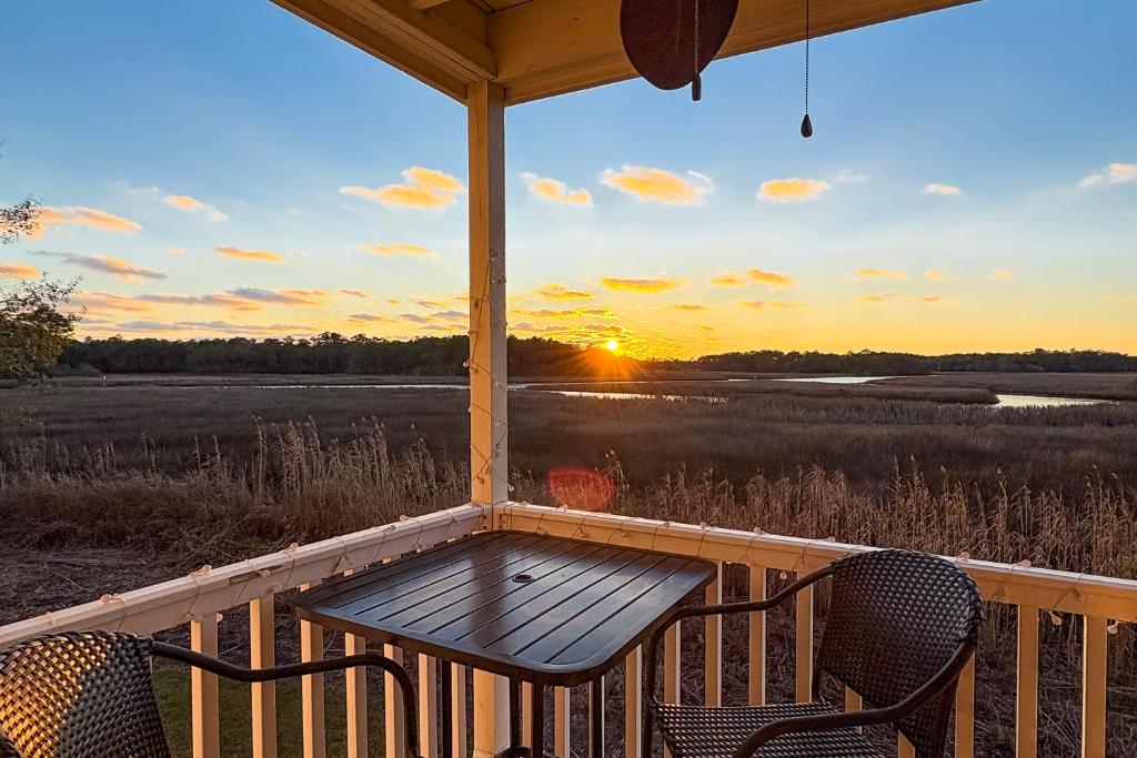 a table and chairs on a porch with the sunset at Waterfront condo at Harbor Landing G02 - Relax in BEAUTIFUL Ocean Springs in Gulf Park Estates