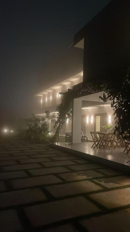 a building on a foggy night with tables and chairs at Pousada Na Serra in Ubajara
