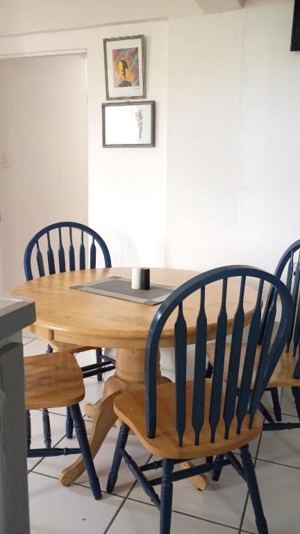 Una mesa de madera con cuatro sillas alrededor. en Zinnia Apartments Antigua, en Potters Village