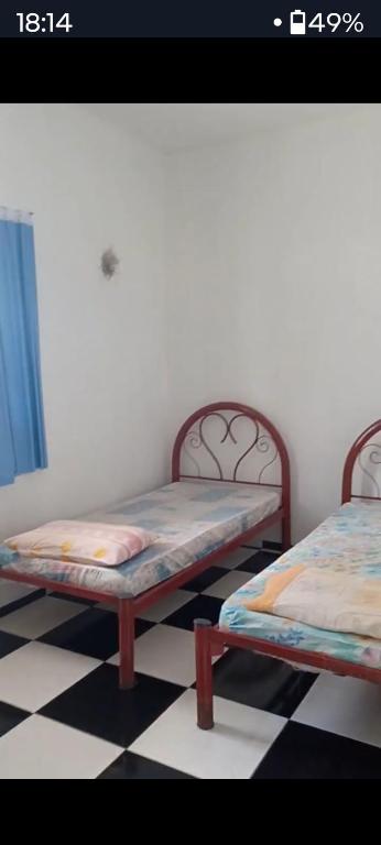 two beds in a room with a checkered floor at Residência dos guimaraes in Belém