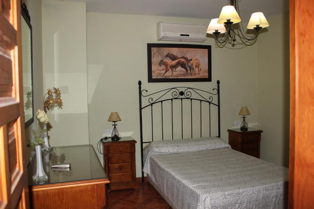 1 dormitorio con 1 cama, 2 mesitas de noche y mesa de cristal en Casa Rural Antikaria, en Antequera