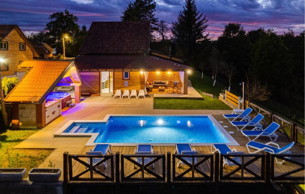 a swimming pool with chairs and a house at Pet Friendly Home In Gornje Dubrave With Sauna in Perići