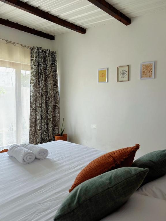 a bedroom with a white bed with pillows and a window at Buena Vista in El Paredón Buena Vista
