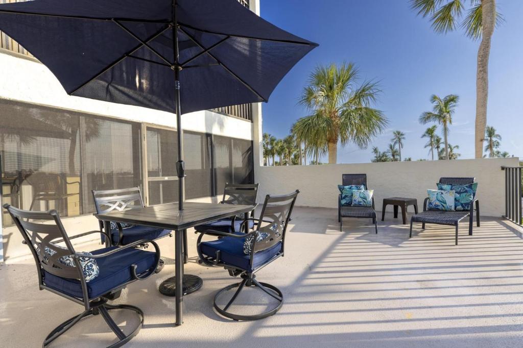 a table with chairs and an umbrella on a patio at 2BR Sandpiper Key - Walk to Beach & Dining in Manasota Key