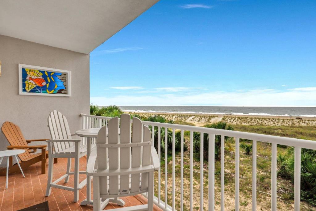 Un balcón con mesa y sillas y la playa. en Ocean Song 324, en Tybee Island