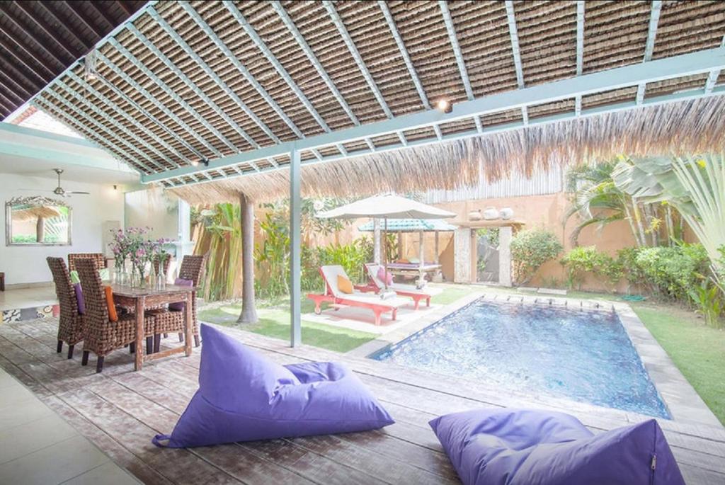 a patio with a pool and a table and chairs at Seminyak Villa Hibiscus in Seminyak