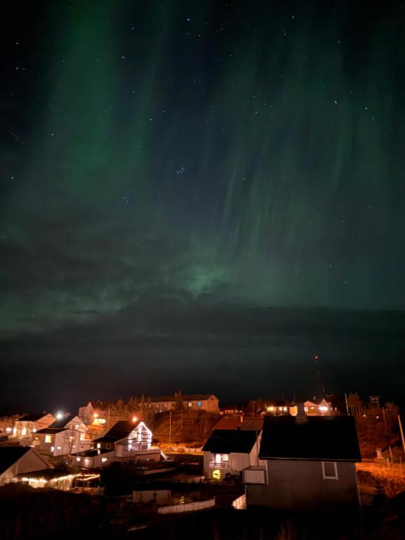 a city at night with the aurora in the sky at KB Storhaugen House - Sørvågen in Moskenes