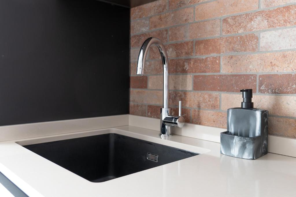 a kitchen with a black sink and a brick wall at Elegant Urban Home - Free Parking - 7min Niguarda in Bresso