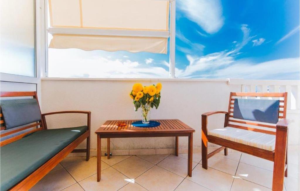 two chairs and a table with a vase of yellow flowers at Lovely Apartment In Omis With Wifi in Tice