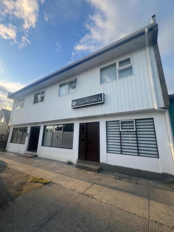 a white building with a sign that reads casework at Hostal Casa Blanca in Puerto Natales