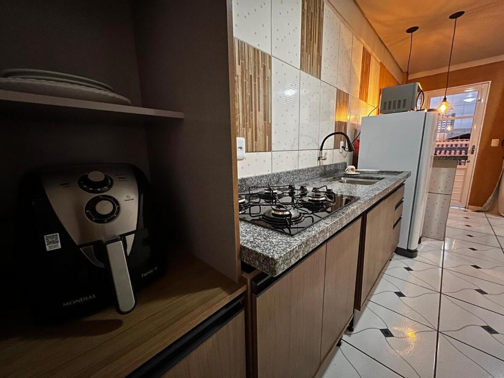 a kitchen with a stove and a refrigerator at Studio prático e bem localizado em Cuiabá in Cuiabá