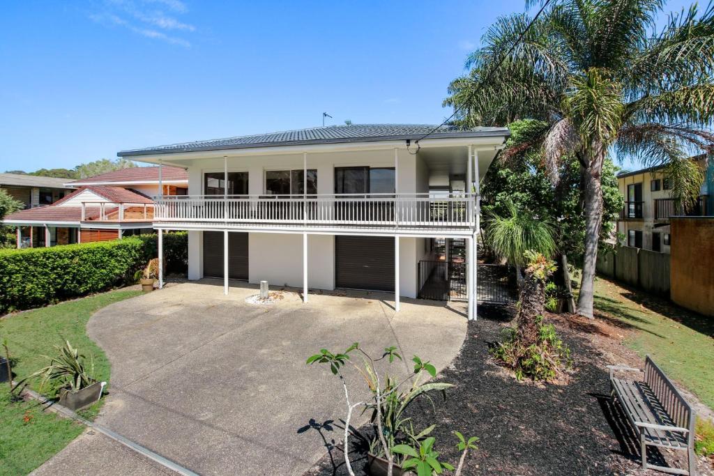 a large white house with a palm tree at Esplanade 123 Golden Beach in Golden Beach