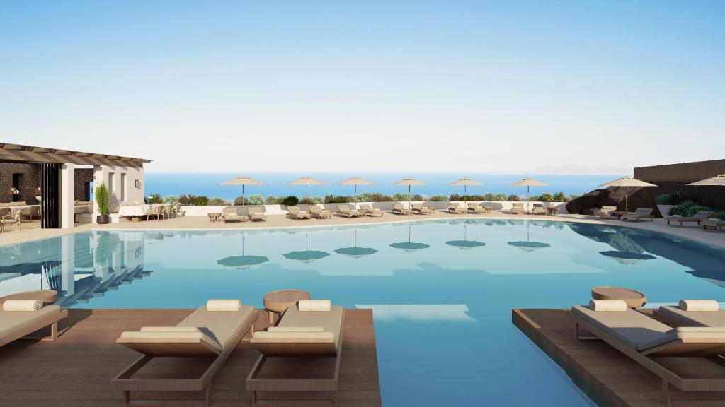una gran piscina con tumbonas y sombrillas en NĒRO Suites by NOMÉE Hospitality Group, en Imerovigli