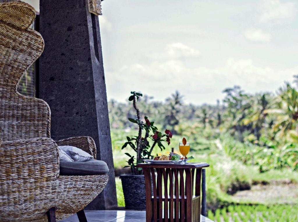 een stoel en een tafel op een veranda met een raam bij Graha Rusni in Ubud