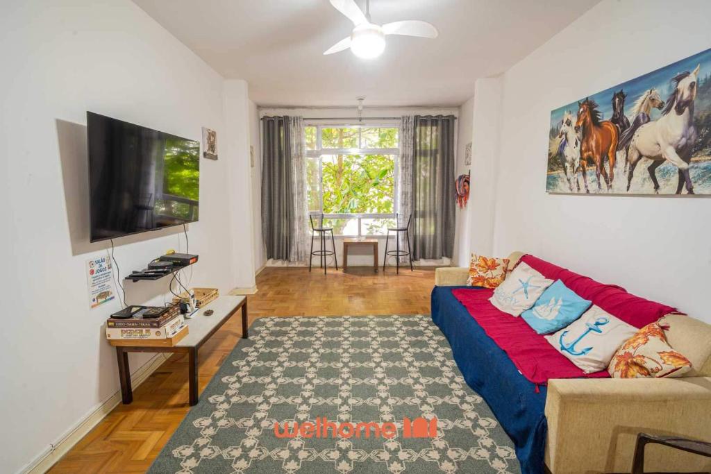 ein Wohnzimmer mit einem blauen Sofa und einem Fernseher in der Unterkunft Apartamento no Guaruja 50m da Praia das Pitangueiras in Guarujá