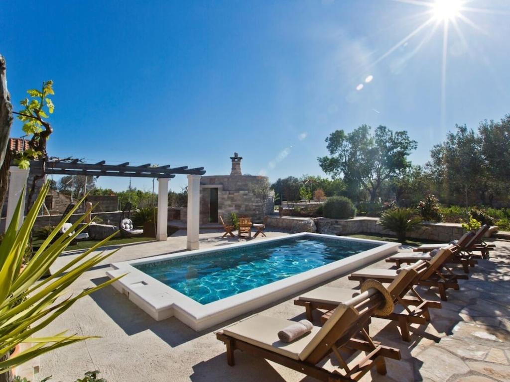 a swimming pool with chaise lounges and a patio with a poolvisor at Villa in Bogomolje with swimming pool in Bogomolje
