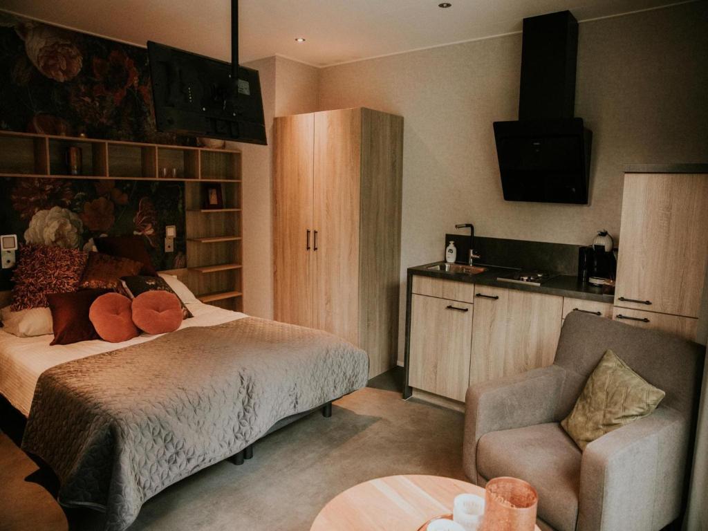 a bedroom with a bed and a chair and a television at Luxury Holiday Loft in Si-Es-An in Balkbrug