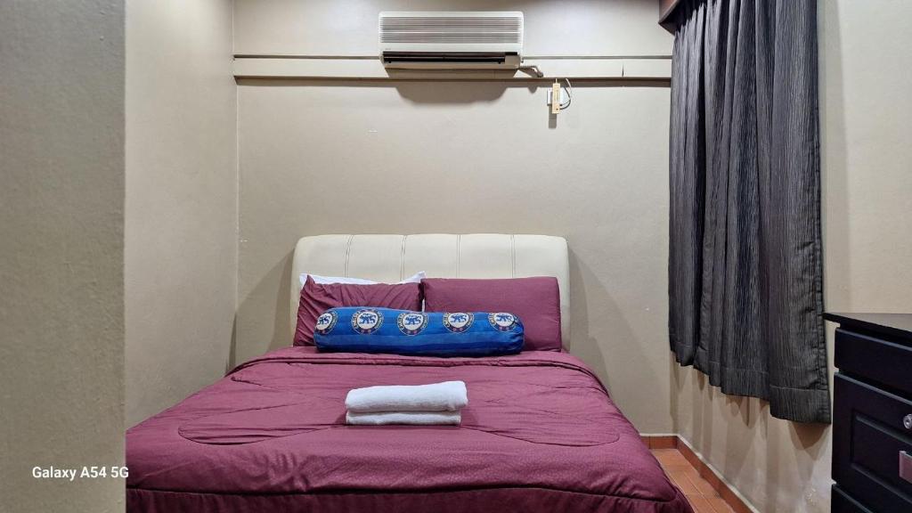 a bed with a purple blanket and two pillows on it at ARIAN GOLDSAND SEAVIEW APARMENT glory beach resort in Port Dickson