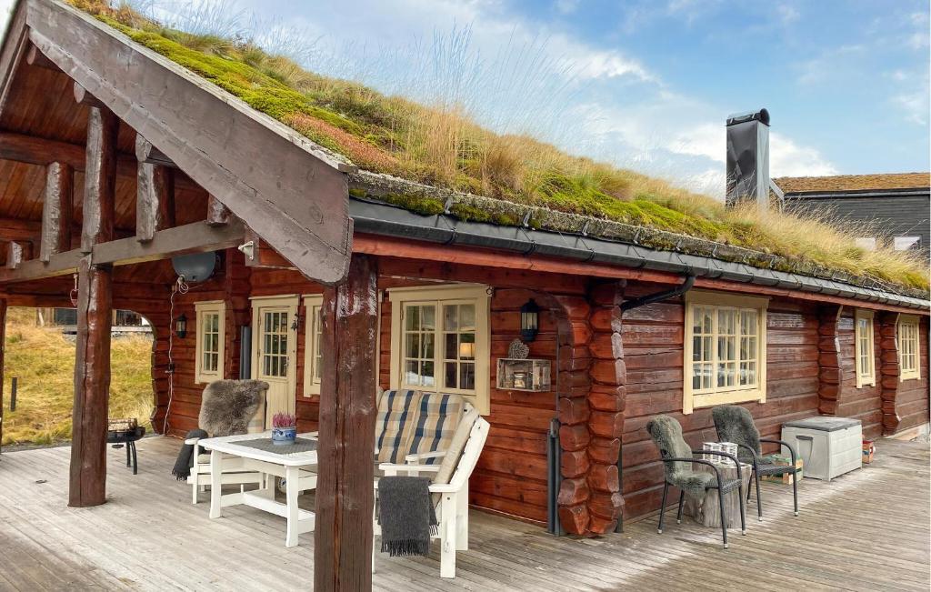 a log cabin with a grass roof with a table and chairs at 3 Bedroom Beautiful Home In Straumgjerde in Brunstad