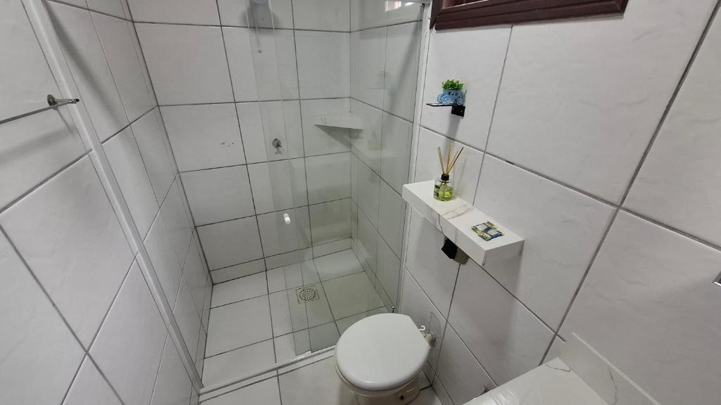 a white bathroom with a toilet and a shower at Residencial DO MAR in Bombinhas