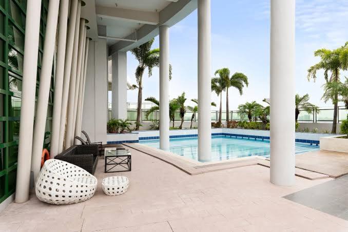 ein Swimmingpool mit Palmen und einem Gebäude in der Unterkunft SWEET MEMORIES CONDOTEL at THE SYMPHONY TOWERS QC in Manila