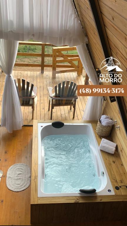 a hot tub in a tent with two chairs at Chalé Alto do Morro 2 - conforto e vista deslumbrante in Rancho Queimado