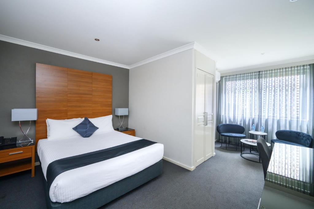 a hotel room with a bed and a desk and chairs at Crest on Barkly Hotel in Melbourne
