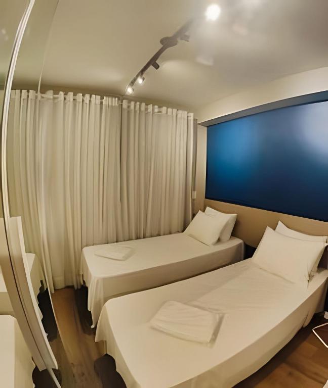 a room with two beds and a blue wall at Flat em São Paulo - Completo e Acolhedor in São Paulo