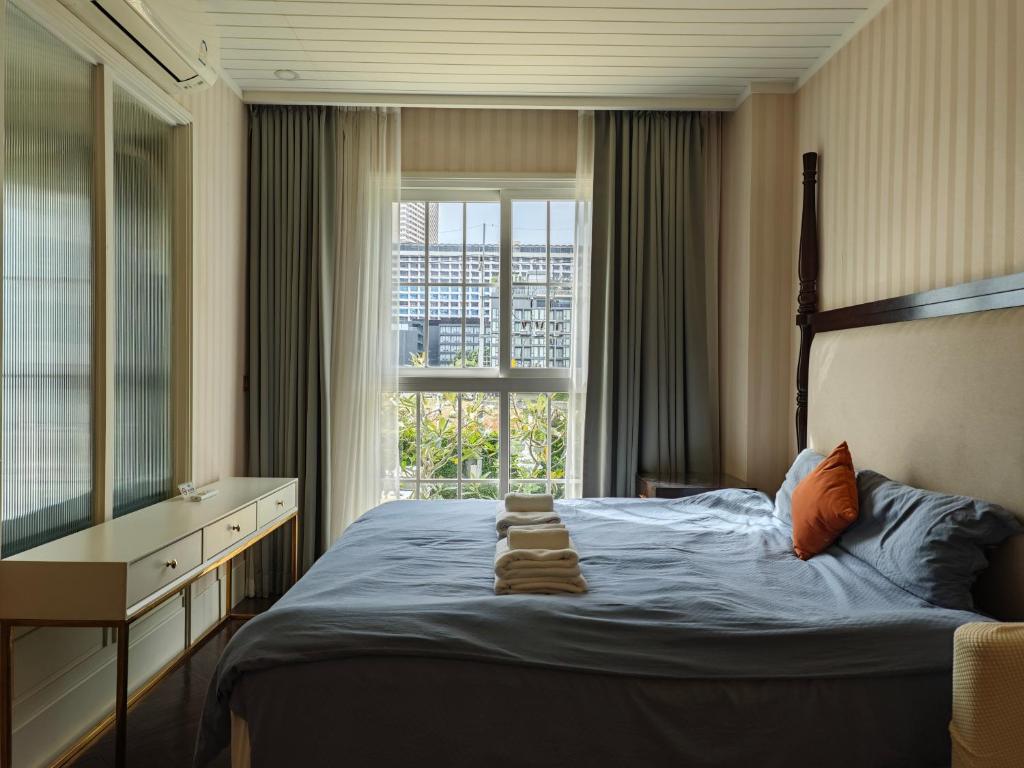 a bedroom with a bed with a dresser and a window at Grand Florida芭提雅带免费游泳池温泉桑拿浴和健身房瑜伽室私家海滩公寓E206 in Na Jomtien