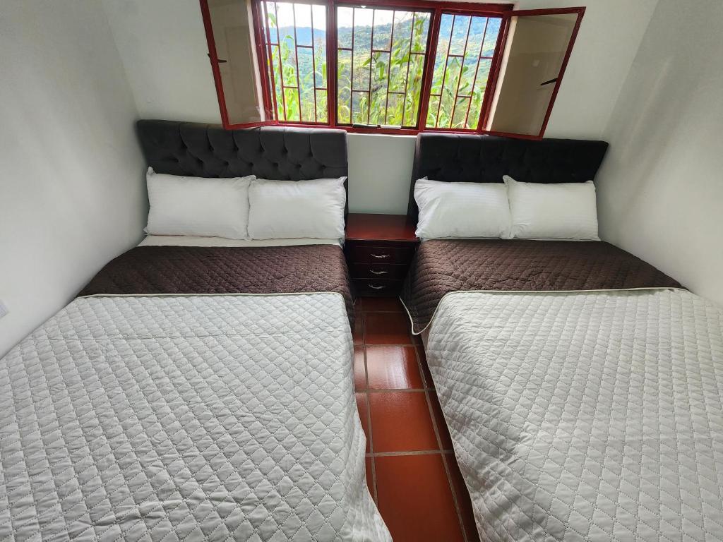 three beds in a small room with a window at Finca Campestre El Descanso in Somondoco