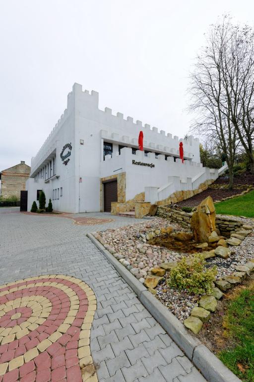 a white building with red statues on the side of it at Restauracja Rycerska in Iłża