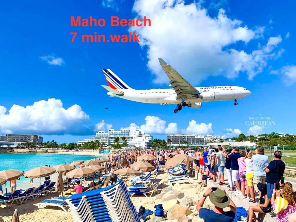 an airplane flying over a beach with a crowd of people at Maho Escape- with Pool and Gym, Lagoon view, walk to Maho Beach and Mullet Bay, walk to dinning in Maho Reef