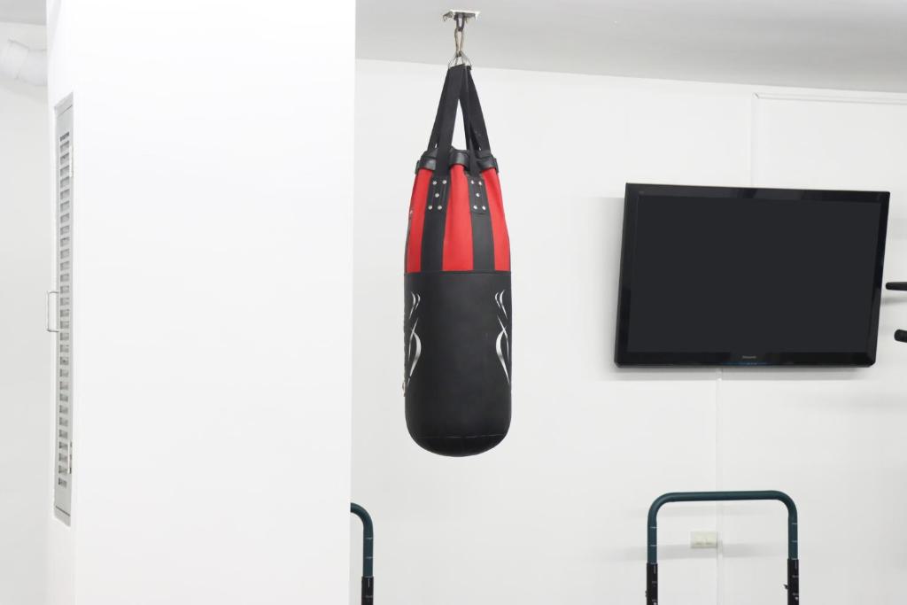 A hanging punching bag beside a wall-mounted television in the fitness room.