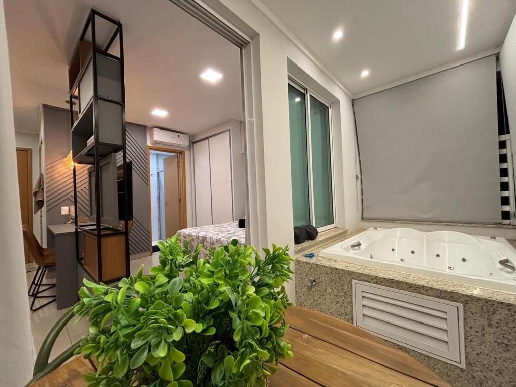 ein Badezimmer mit einer Badewanne und einem Tisch mit einer Pflanze in der Unterkunft Flat | Linda vista | Ao lado do Goiânia Shopping in Goiânia