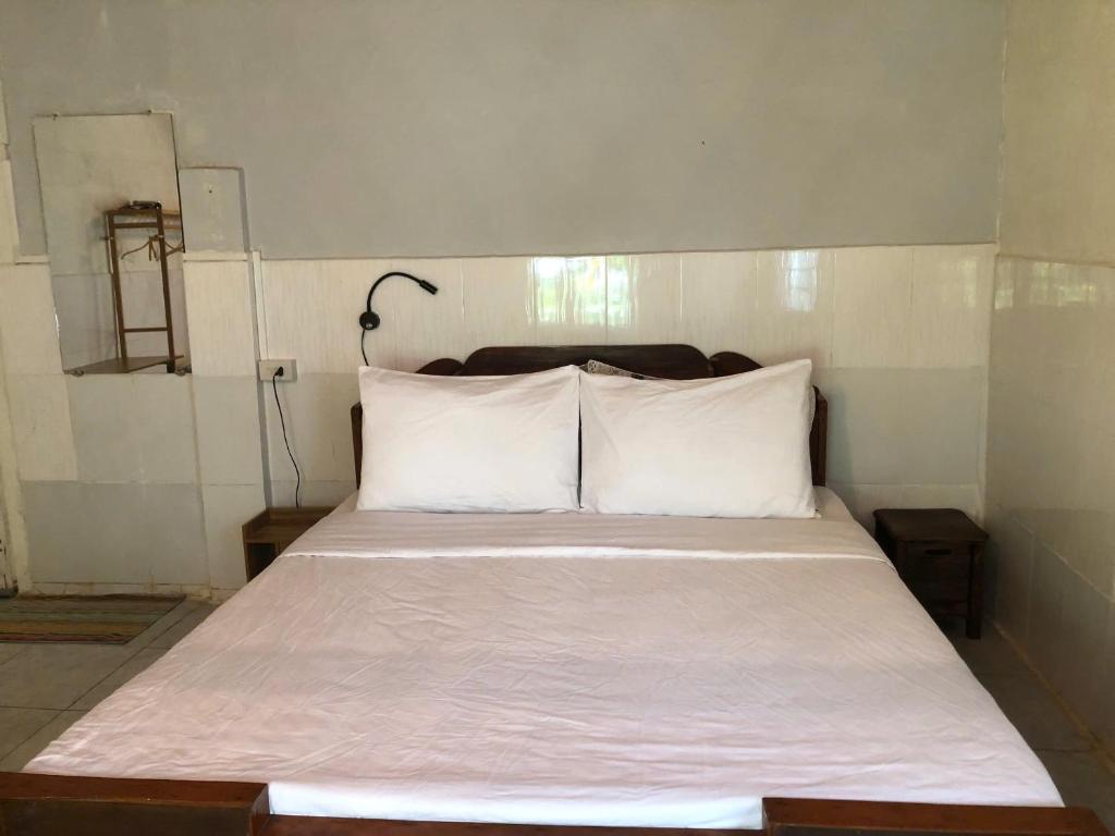 Una cama con sábanas blancas y almohadas en una habitación. en Dorm Can Tho, en Can Tho
